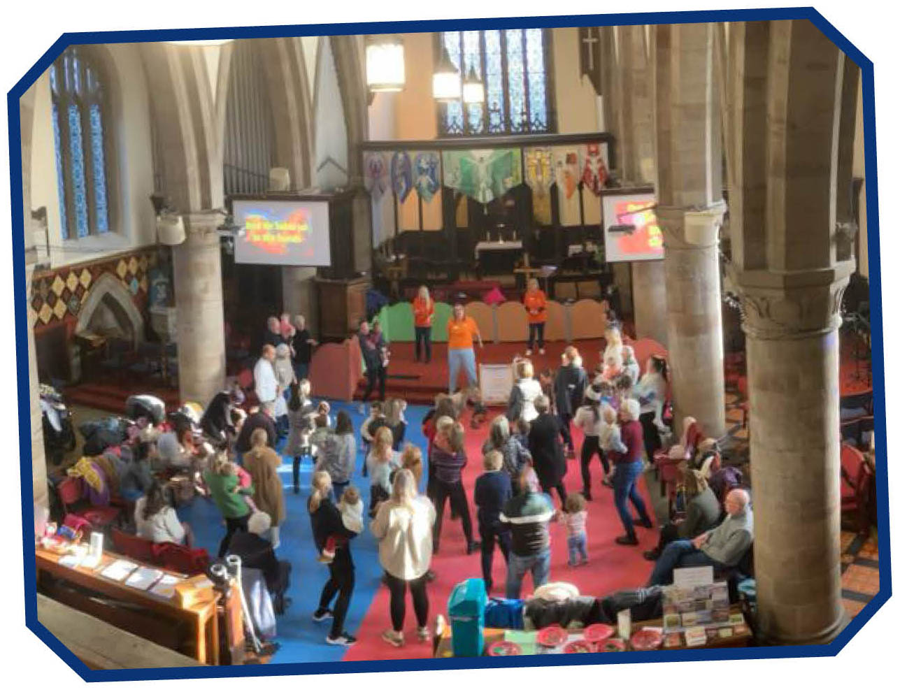 parents and toddlers in a large cleared space at the front of church singing an action song