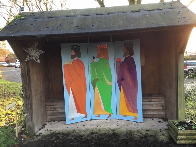 Bus shelter with 3-panel images of the kings in bright colours. The panels are each 6 feet high and about 2 feet wide