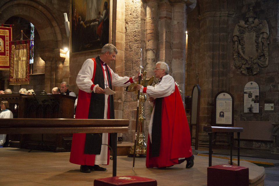 Bishop Mark symbolically ends his term as bishop by giving his crosier (bishop's staff) to Bishop Michael